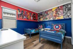 Discover a vibrant kids' room filled with superhero murals and bright blue accents. Cozy twin beds with lively bedding invite playful dreams, while the modern wood flooring adds warmth and style for your little ones to enjoy.