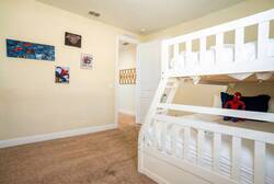 This cheerful children's bedroom boasts a charming white bunk bed for shared adventures and vibrant Spider-Man artwork, creating a cozy, carpeted space that sparks imagination and creativity.