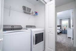 This stylish laundry area boasts modern appliances in a bright, clean space, making it easy to refresh your wardrobe during your stay. Enjoy the comfort of soft carpet underfoot as you step into the adjoining room.