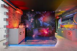 Enter a lively entertainment room featuring a stunning cosmic mural that enhances the atmosphere. The dim lighting and colorful LED accents create the perfect setting for memorable movie nights or game sessions with friends.