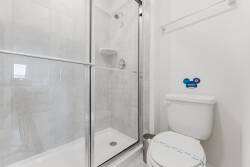 Experience a bright, clean bathroom with sleek glass shower doors and modern fixtures in a fresh white palette. Enjoy ample space for your toiletries, adding comfort and style to your stay.