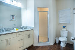 This bright bathroom boasts a sleek granite countertop and cream cabinetry, creating a clean, inviting space. Enjoy the spacious walk-in shower and modern fixtures for a refreshing start or end to your day.