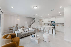 Step into a bright, airy living area where soft gray furnishings harmonize with warm wooden accents. The open layout seamlessly connects the cozy seating with a stylish kitchen, inviting you to relax or whip up a delicious meal.