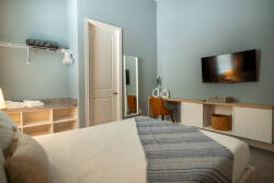 Relax in this thoughtfully designed bedroom featuring soft blue walls that create a calming atmosphere. The cozy bed is complemented by modern storage solutions, while a sleek TV invites you to unwind after a day of exploring.