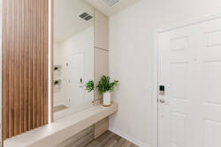 Step into a bright and airy entryway featuring sleek wood paneling and a spacious bench that invites you to unwind. The contemporary mirror reflects natural light, creating an uplifting atmosphere perfect for starting your day.