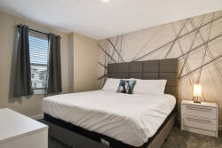 This cozy bedroom is adorned with a stylish upholstered headboard and soft white linens, inviting relaxation. Natural light pours in, enhancing the contemporary decor and creating a peaceful atmosphere for restful nights.