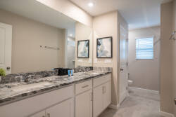 Indulge in luxury in this stylish bathroom featuring a sleek granite countertop and modern cabinetry. The bright ambiance enhances your space, making it the ideal setting to elevate your morning routine with sophistication.