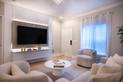 Relax in this bright living area featuring plush cream seating and a sleek wall-mounted TV. The minimalist coffee table and soft drapes enhance the inviting atmosphere by allowing natural light to fill the space.