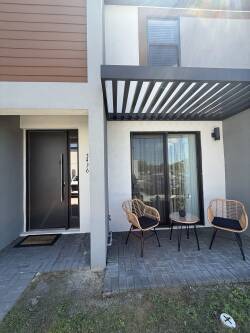 Step into a welcoming entrance with a sleek black door and modern outdoor seating, perfect for morning coffee. The textured stone patio complements the contemporary design, creating a stylish entryway to your next adventure.
