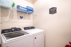 Enjoy a functional laundry room with modern appliances to keep your clothes fresh during your stay. Neatly organized shelves and a cheerful sign add charm and convenience to enhance your vacation experience.