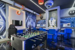 Experience a lively game room filled with fun and adventure, showcasing a stylish foosball table and eye-catching blue seating. Captivating murals and modern lighting bring an energetic vibe to this vibrant space.