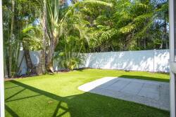 Step outside to your private oasis, where lush greenery meets a well-manicured lawn. The clean lines of the stone patio offer a perfect spot for morning coffee or evening relaxation amid the tropical ambiance.