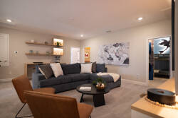 This cozy living room invites relaxation with a plush sectional sofa and stylish leather chairs, all enhanced by warm lighting that highlights unique world map art, creating a perfect atmosphere for guests to unwind.