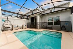 Relax in a private screened pool area with sparkling water, a cozy hanging chair, outdoor seating, safety fence, and open sky views, creating a comfortable space for family vacation moments.