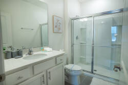 Experience a bright bathroom with sleek glass shower doors and a spacious vanity featuring clean white cabinetry. The minimalist decor and natural light create a refreshing atmosphere for your stay.