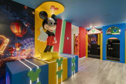 Welcome to a vibrant playroom filled with color, highlighted by a striking Mickey Mouse centerpiece and imaginative wall murals. The bold blue and yellow accents make this space perfect for energetic family fun.
