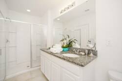 This bright bathroom boasts a sleek granite countertop and classic white cabinetry for a refreshing feel. The spacious glass shower invites relaxation, and a touch of greenery adds warmth to the space.