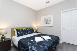 Experience restful nights in this cozy bedroom featuring a plush bed adorned with floral linens and crisp white towels. Soft lighting from bedside lamps creates a warm glow, while simple decor adds a touch of charm to the space.