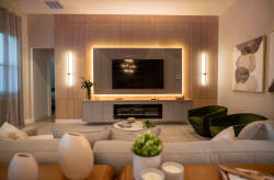 Relax in our cozy living room, featuring plush green seating and a stylish wooden entertainment unit with ambient lighting. Enjoy the soft textures and tasteful decor for a warm, inviting atmosphere perfect for unwinding.