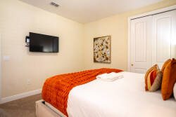 Bright and cozy, this room features a plush bed adorned with warm, textured throws that invite relaxation. The soft beige walls complement contemporary artwork, while a wall-mounted TV adds modern convenience for your downtime.
