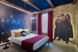 Discover a whimsical bedroom with vibrant blue beams and warm wooden accents, creating a cozy vibe. Relax among captivating wall art of beloved characters and enjoy plush bedding with a rich red throw after your day of adventure.