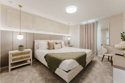 Enjoy peaceful nights in this beautifully designed bedroom with soft beige tones and plush carpeting. The cozy bed, dressed in textured pillows and a warm throw, invites relaxation with its soothing layered lighting.