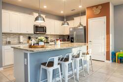 Cook with ease in a bright fully equipped kitchen with white cabinets, granite countertops, stainless steel appliances, pendant lights, and a spacious island perfect for family meals.
