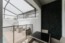 Enjoy a cozy outdoor nook featuring a sleek black table and woven seating, perfect for sipping your morning coffee. This stylish space, enclosed by a modern mesh, offers comfort and a lovely view of the inviting pool.
