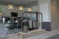 Enjoy meals and conversations in a thoughtfully designed space where stylish pendant lights illuminate a rustic wood centerpiece, perfectly complementing modern bar stools and offering a view of the sleek kitchen.