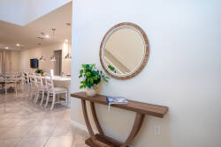 Welcome to a cozy entryway with a stylish wooden console table, a potted plant, and a lovely round mirror that enhances the soft lighting. The open layout flows into a spacious dining area, ideal for memorable gatherings.