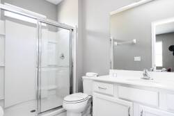 Welcome to this bright bathroom, where sleek white cabinetry and a spacious glass shower provide a refreshing start to your day. The large mirror amplifies natural light, creating a clean and airy space perfect for relaxation.