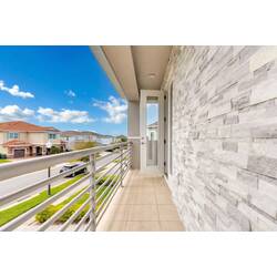 Step onto a private balcony with a sleek railing, stone accent wall, tiled flooring, and open neighborhood views under the bright Florida sky, perfect for a quiet moment outdoors.
