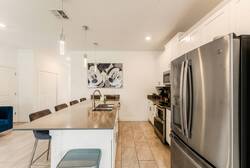 Cook with ease in a bright kitchen with white cabinets, stainless steel appliances, dark tile backsplash, countertop appliances, and plenty of storage, creating a practical space for family meals during vacation.