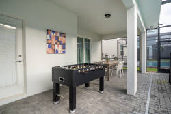 Step into this shaded outdoor lounge, where a stylish foosball table invites friendly competition. Light pours in through large windows, illuminating the modern decor and creating a lively atmosphere perfect for gathering.