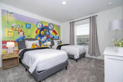 This bright bedroom features two cozy twin beds with crisp white linens for restful nights. A playful mural, soft gray carpeting, and stylish curtains create a warm ambiance, enhanced by natural light streaming in.