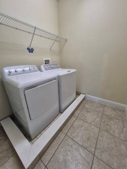 Enjoy the convenience of this functional laundry area with modern appliances set against a clean backdrop. The spacious design includes a handy shelf for easy organization of your essentials during your stay.