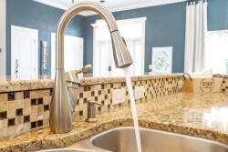 Enjoy culinary delight in this beautiful kitchen with a sleek stainless steel faucet and spacious granite countertop, complemented by a mosaic tile backsplash and rich blue walls that bathe the space in natural light for.