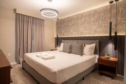 Enjoy a restful night in this beautifully designed bedroom with a plush bed and soft linens. The unique circular light fixture and textured accent wall create a cozy ambiance, while elegant curtains add charm to the window.
