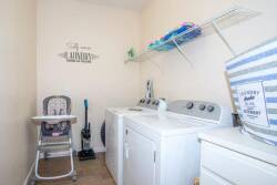 This practical laundry room features spacious appliances alongside neatly organized shelving, ensuring convenience during your stay. A subtle coastal decor element adds a touch of charm, making chores feel less like a task.