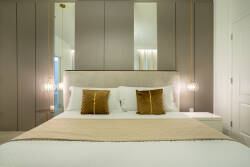 Step into a restful bedroom where soft neutral tones and rich golden accents create a soothing ambiance. The plush bedding invites relaxation, while stylish pendant lights add a touch of sophistication to your stay.