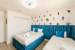 Bright and playful, this room features two comfortable beds with soft, teal headboards that invite relaxation. The fun, colorful wall art adds a whimsical touch, creating a cheerful atmosphere for a rejuvenating stay.