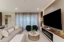 This bright and airy living room invites relaxation with its plush sectional sofa and stylish green accent chairs. Soft curtain textures enhance the chic coffee table, creating a warm and welcoming atmosphere for guests to enjoy.