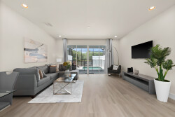 Unwind on the cozy gray sofa adorned with colorful pillows, basking in the natural light from sliding doors that open to your private pool.