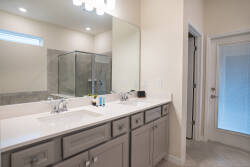 This bright and spacious bathroom boasts a double vanity with stylish light-gray cabinetry and plenty of counter space for your morning routine. Enjoy the modern walk-in shower and the natural light streaming in from the window.