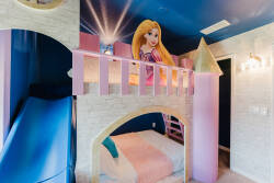 Discover a whimsical hideaway with a charming playhouse loft in vibrant pink, ideal for imaginative adventures. The cozy sleeping area below, with soft textures and playful decor, adds to the delightful atmosphere for your stay.