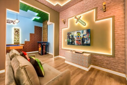 Welcome to a vibrant living area where comfort meets playful design. A cozy couch with colorful pillows and a striking LED-lit wall create an inviting space for relaxation and fun, making it the perfect spot for gatherings.
