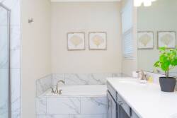 The bathroom features elegant marble accents and a spacious soaking tub, perfect for unwinding after a day of adventure. Soft natural light fills the room, highlighting the tasteful decor and inviting warmth of the space.