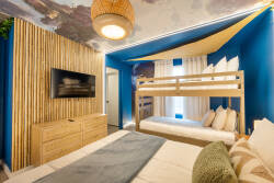 Enjoy a unique sleeping experience in this vibrant bedroom, featuring playful bunks against rich blue walls and natural wood accents. Cozy bedding and stylish decor create a warm, inviting atmosphere for everyone.