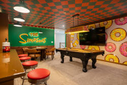 Enter a vibrant entertainment zone filled with colorful donut patterns and a bold checkerboard ceiling. Cozy red bar stools surround a sleek pool table, inviting you to enjoy fun competitions with friends.