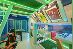 Enjoy a soccer themed gaming nook with framed jerseys, stadium wall art, arcade controls, LED lighting, soccer ball decor, and a colorful seat, creating a fun space for vacation entertainment.